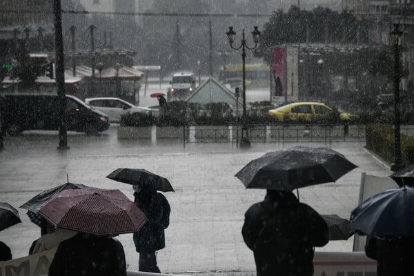 Κόσμος στην βροχή με τις ομπρέλες τους