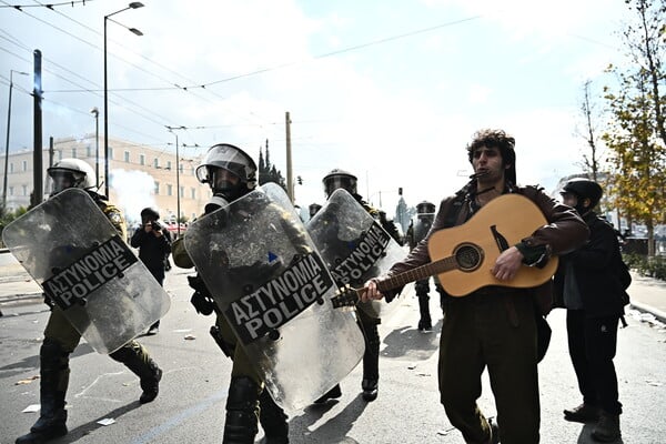 Πορεία για τα Τέμπη στην Αθήνα: Μουσικός με την κιθάρα του δίπλα από τα ΜΑΤ την ώρα των επεισοδίων